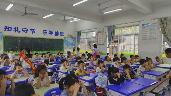 志愿者在协助老师检查眼保健操情况